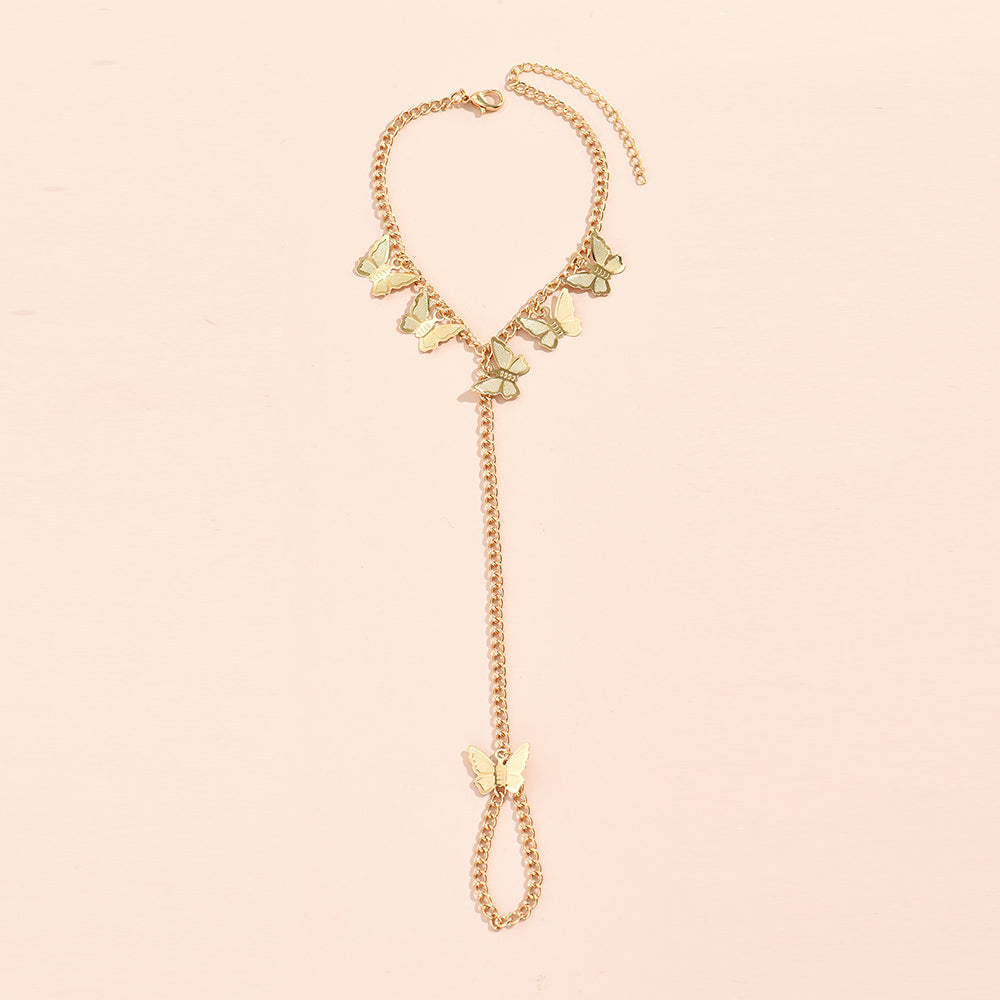 Gold curb chain bracelet hung with five flat butterfly charms, a chain running to a butterfly-topped chain finger loop