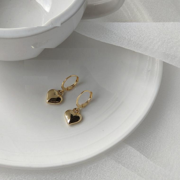 Small gold-tone huggie hoops, each with a smooth puffed heart charm hanging below
