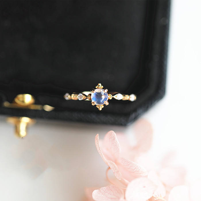 Thin gold-tone ring with a small round blue moonstone and tiny clear side stones