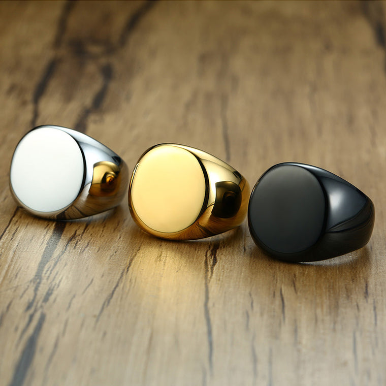 Chunky round-faced signet rings shown polished, in gold, steel and black