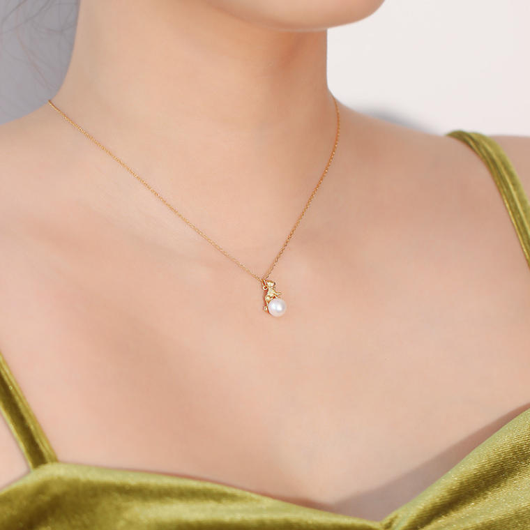 Fine gold-tone chain with a small cat figure sitting on a round pearl
