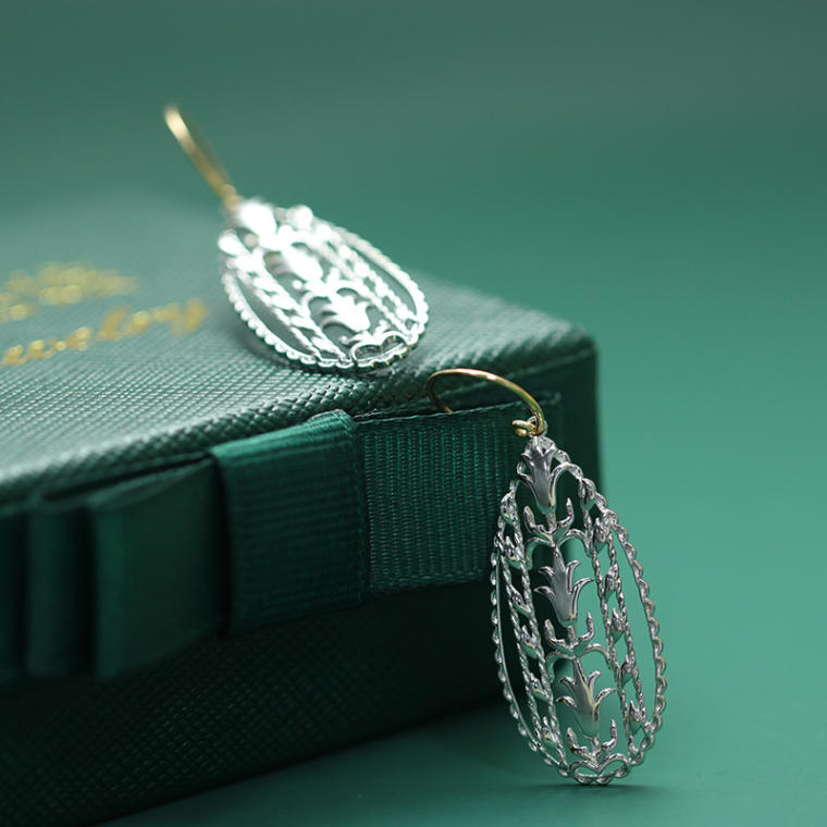 Openwork silver-tone teardrop earrings hanging from gold-tone hook wires