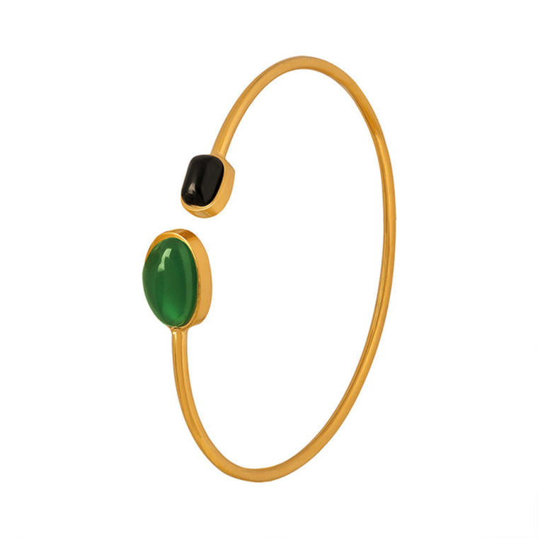 Slim gold-tone open bangle with a smooth green resin oval at one end of the opening and a small black resin rectangle at the other