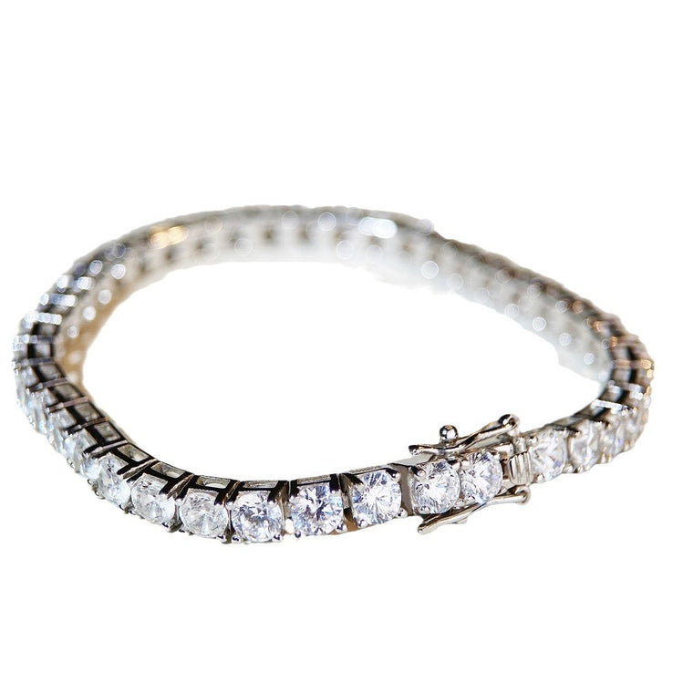 Single-row tennis bracelet of round prong-set stones, shown on a neutral ground and worn on the wrist